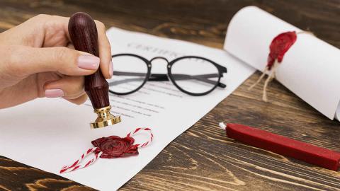 Dokument mit rotem Siegel, Dokumentenrolle, Brille Siegelwachs auf Tisch
